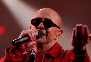 Indio Solari cantando con campera roja y micrófono