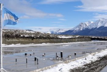 Sector de la Base Naval Integrada de Ushuaia, con la bandera argentina y las montañas al fondo.