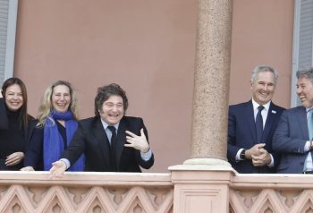 Milei con funcionarios en balcón, encuadre horizontal; distinto del retrato parlamentario y del acto industrial.