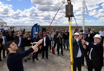 Acto real al aire libre, con cascos, instalación de gas y autoridades; plano amplio.